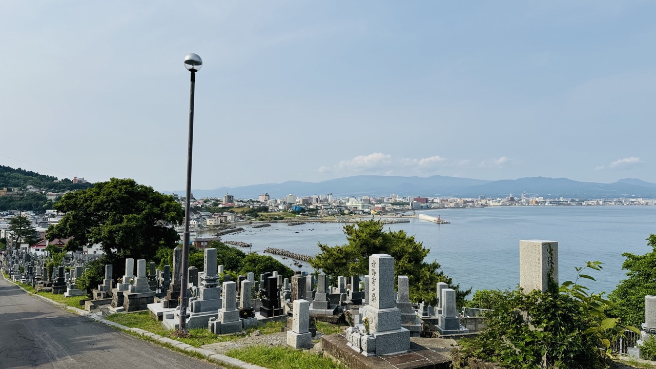 函館立待岬へ向かう坂道の両側に所狭しと墓石が立ち並ぶ墓地と坂の途中から一望できる函館市の街並みと海岸